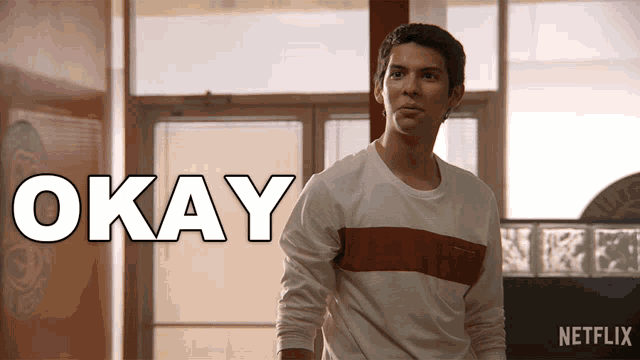 a man in a white shirt is standing in front of a sign that says okay