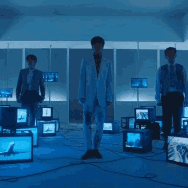 a man in a suit is standing in a room with many televisions