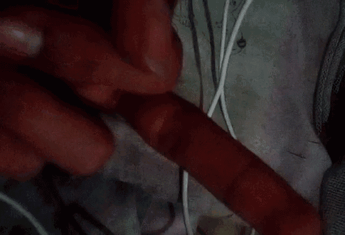 a close up of a person 's hand holding a red object and a white cord