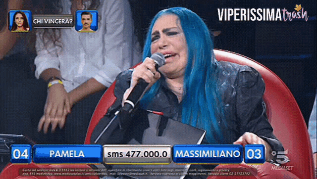 a woman with blue hair is singing into a microphone on a television show