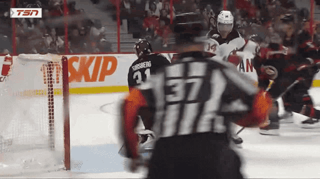 a hockey player with the number 37 on his jersey stands in front of a sign that says skip