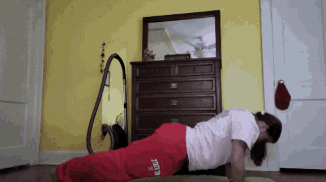 a woman doing push ups in front of a mirror and a dresser
