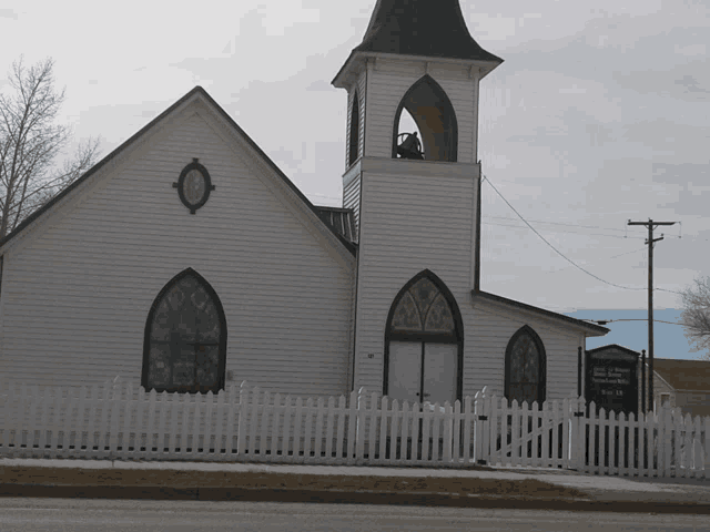 a white church with a black steeple and stained glass