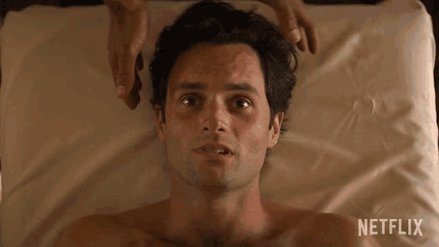 a shirtless man is laying on a bed with a netflix logo behind him
