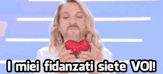 a man with a beard is holding a red heart in his hands and says i miei fidanzati siete voi