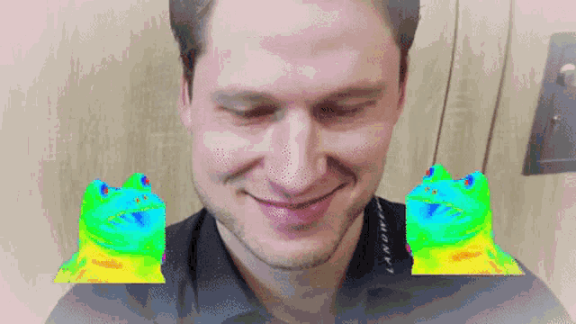 a man is smiling with two frogs in front of his face and the word landre is on his shirt