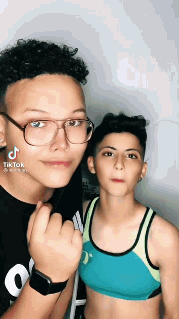 a boy and a girl are standing next to each other and the girl is wearing a crop top and the boy is wearing glasses