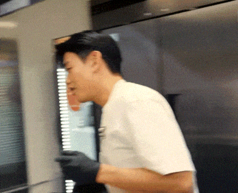 a man in a white shirt and black gloves is standing in front of a refrigerator