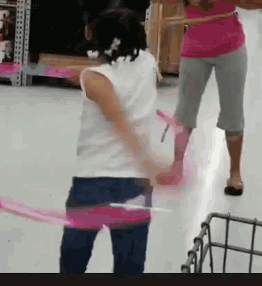 a girl in a white shirt is playing with a pink ribbon