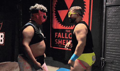 two men wrestling in front of a sign that says the fallo shel