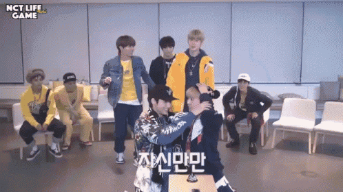 a group of young men are standing in a room with nct life game written on the bottom of the screen