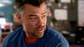 a man with a beard is wearing a blue shirt and looking at something .