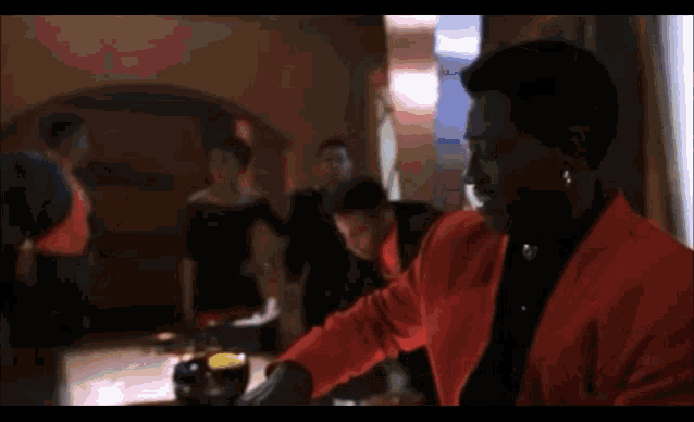 a man in a red jacket is sitting at a table