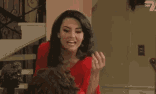 a woman in a red shirt is standing next to a man in a living room and making a funny face .