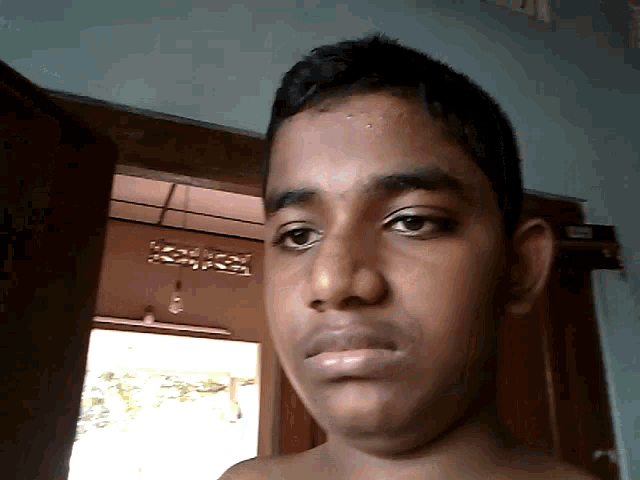 a boy without a shirt looks at the camera with a serious look on his face