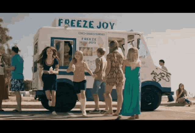 a group of people are standing in front of an ice cream truck called freeze joy