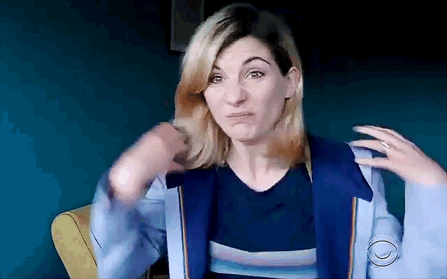 a woman wearing a blue jacket and a blue shirt is making a funny face .