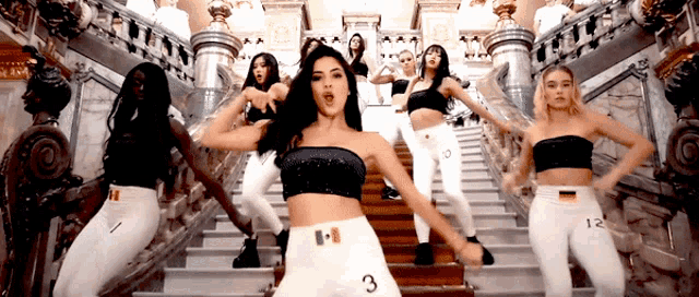 a group of women are dancing on a set of stairs with the number 3 on the bottom of their white pants