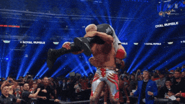 a wrestler is doing a flip over another wrestler in front of a crowd at a wrestling event