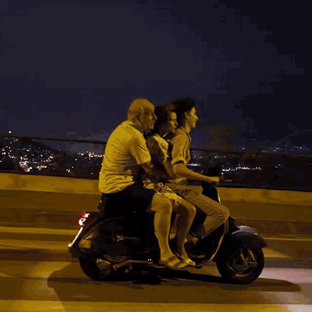 a group of people are riding on a scooter at night