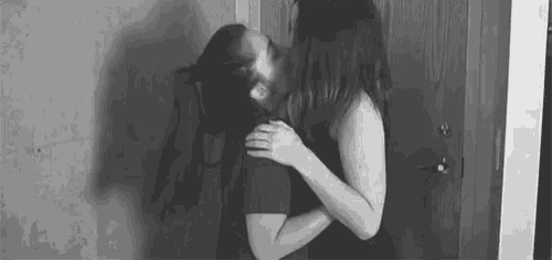a black and white photo of a woman kissing a man on the cheek .