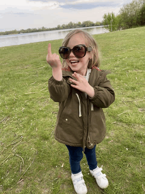 a little girl wearing sunglasses giving a middle finger