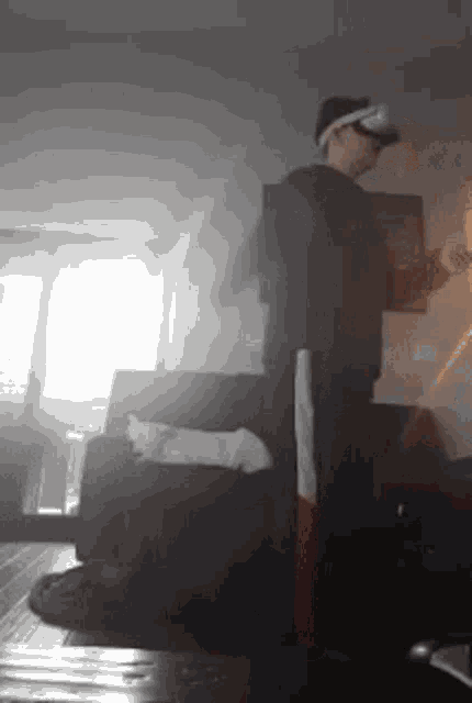 a man wearing a virtual reality headset is standing in a living room next to a couch .