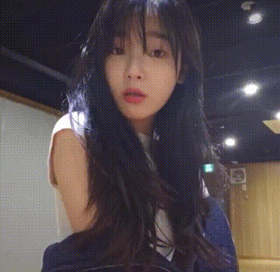 a woman with long black hair is standing in a dark room looking at the camera .