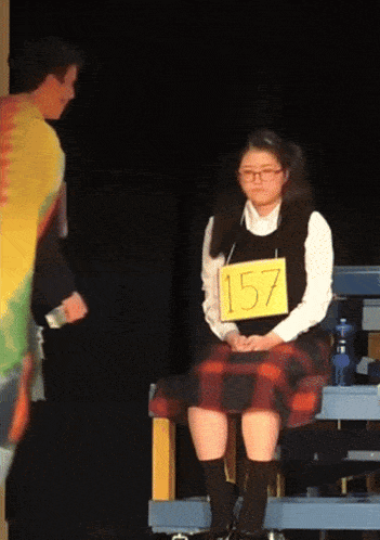 a girl in a plaid skirt has a sign on her chest that says 157