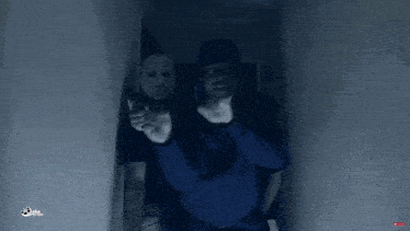 a man in a blue hoodie is pointing a gun and wearing a mask