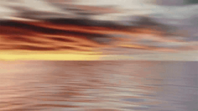 a sunset over a body of water with a cloudy sky