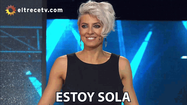 a woman stands in front of a screen that says eltrecetv.com on it