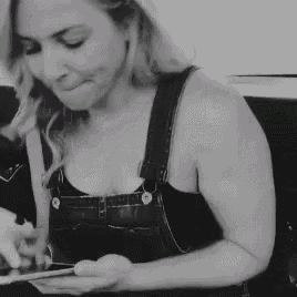 a woman in overalls is using a tablet in a black and white photo .