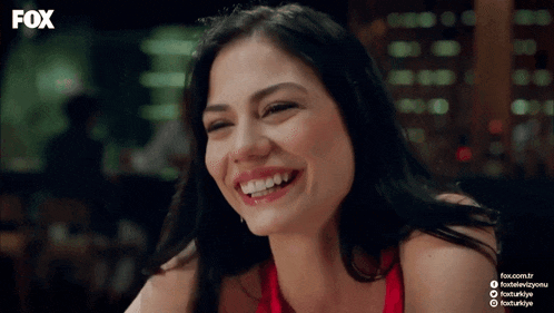 a woman in a red dress is smiling in front of a fox logo
