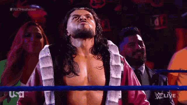 a man in a robe is standing in a wrestling ring while a woman looks on ..