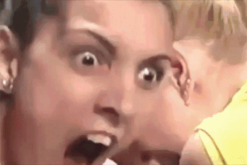 a close up of a woman 's face with her mouth open and a child behind her .