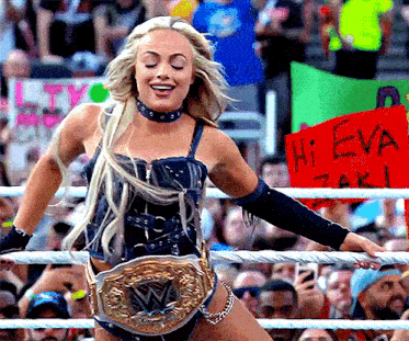a woman in a wrestling ring holds a sign that says hi eva taki