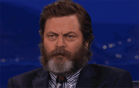 a man with a beard wearing a suit and tie looks at the camera