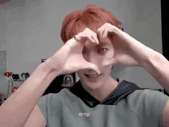 a man with red hair is making a heart with his hands .
