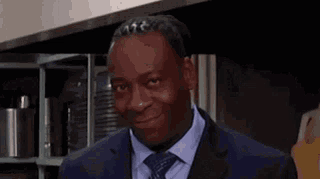 a man in a suit and tie is smiling in a kitchen .