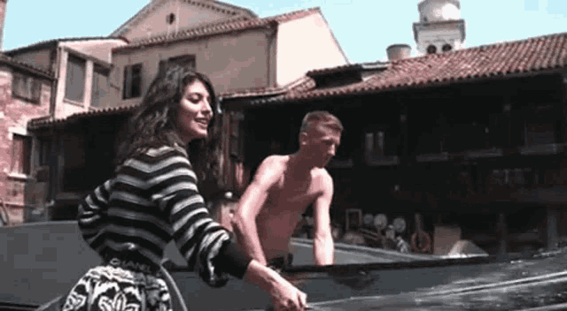 a woman in a striped sweater is standing next to a man in a boat