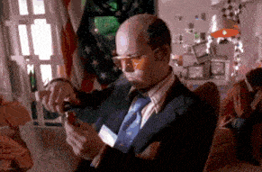 a bald man in a suit and tie is holding a lighter in his hand