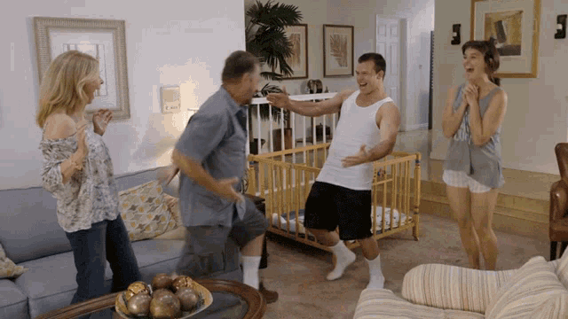 a family is dancing in a living room with a crib in the background