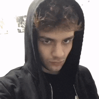 a young man wearing a black hoodie takes a picture of himself