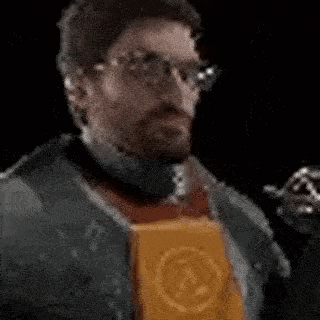a man with glasses and a beard is drinking from a bottle while holding a bag of chips .