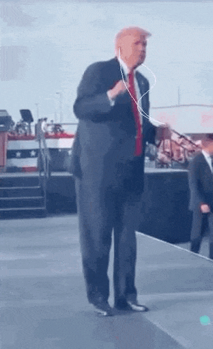 a man in a suit and tie is dancing on a stage while wearing headphones .