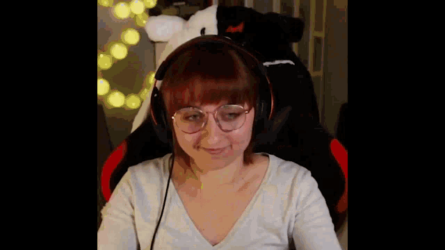 a woman with glasses and headphones is making a heart shape with her hands .