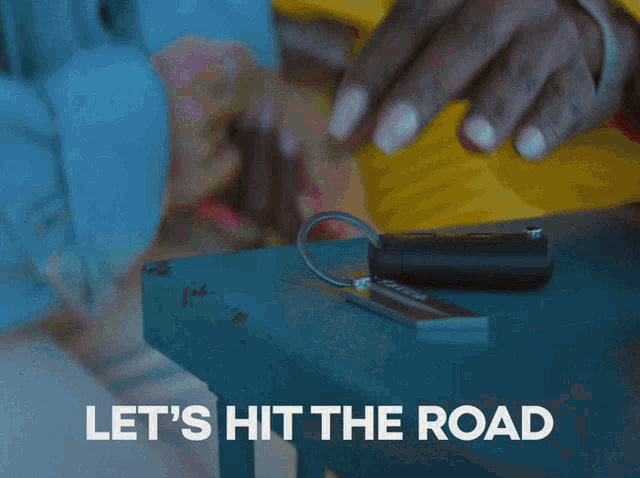a person is putting a key on a table with the words let 's hit the road written below them