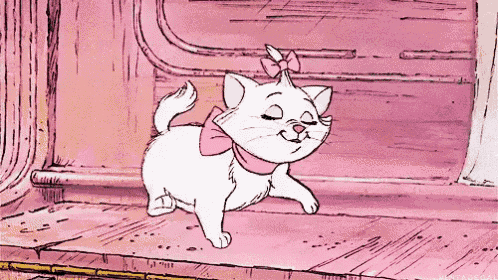 a white cat with a pink bow around its neck is walking on a wooden floor