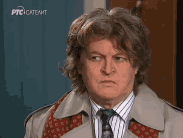 a man wearing a trench coat and tie is on a ptc satellite channel